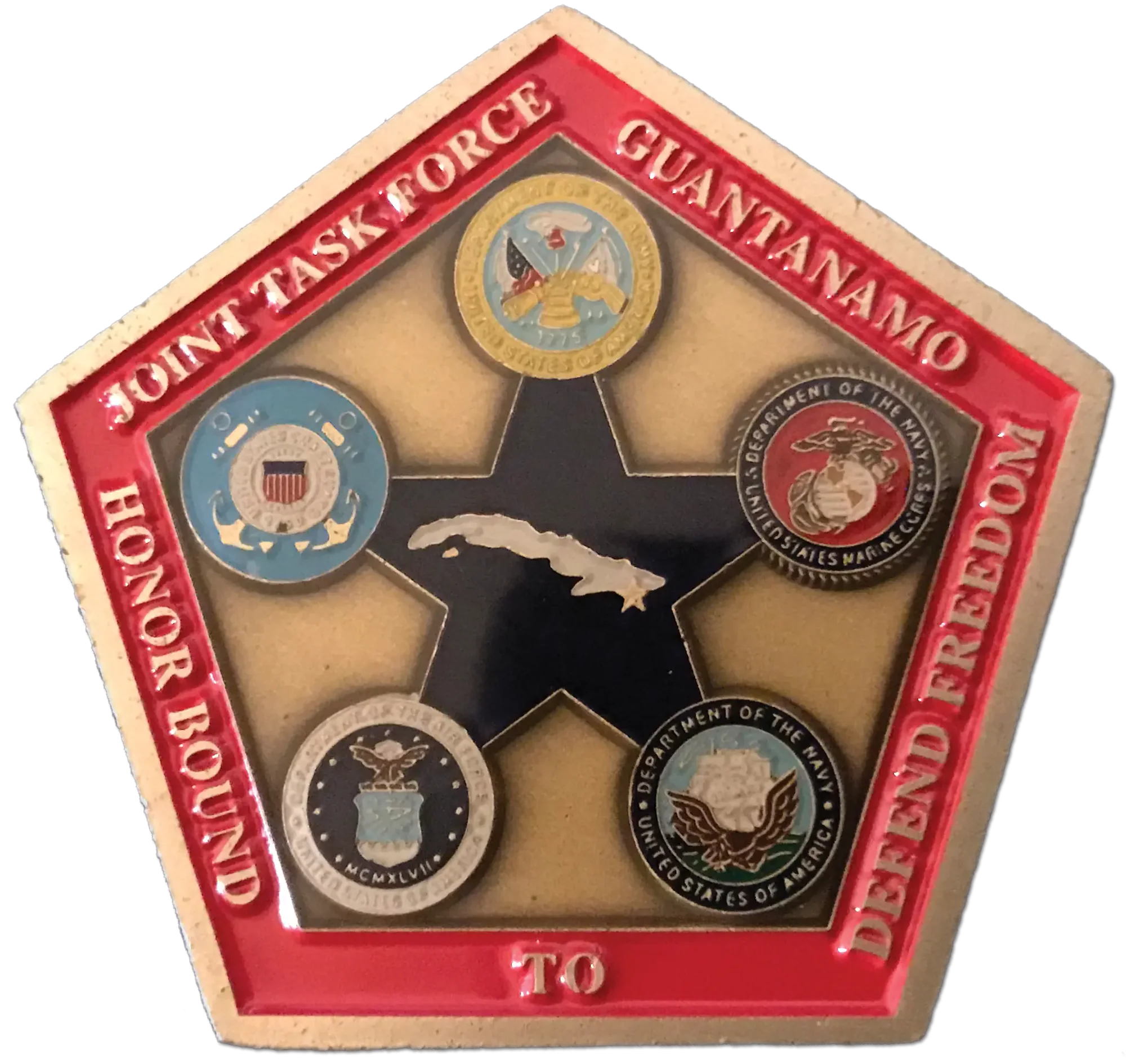 A pentagonal challenge coin reading “Joint Task Force Guantanamo — Honor Bound to Defend Freedom,” set with the seals of the five services around an outline of Cuba.