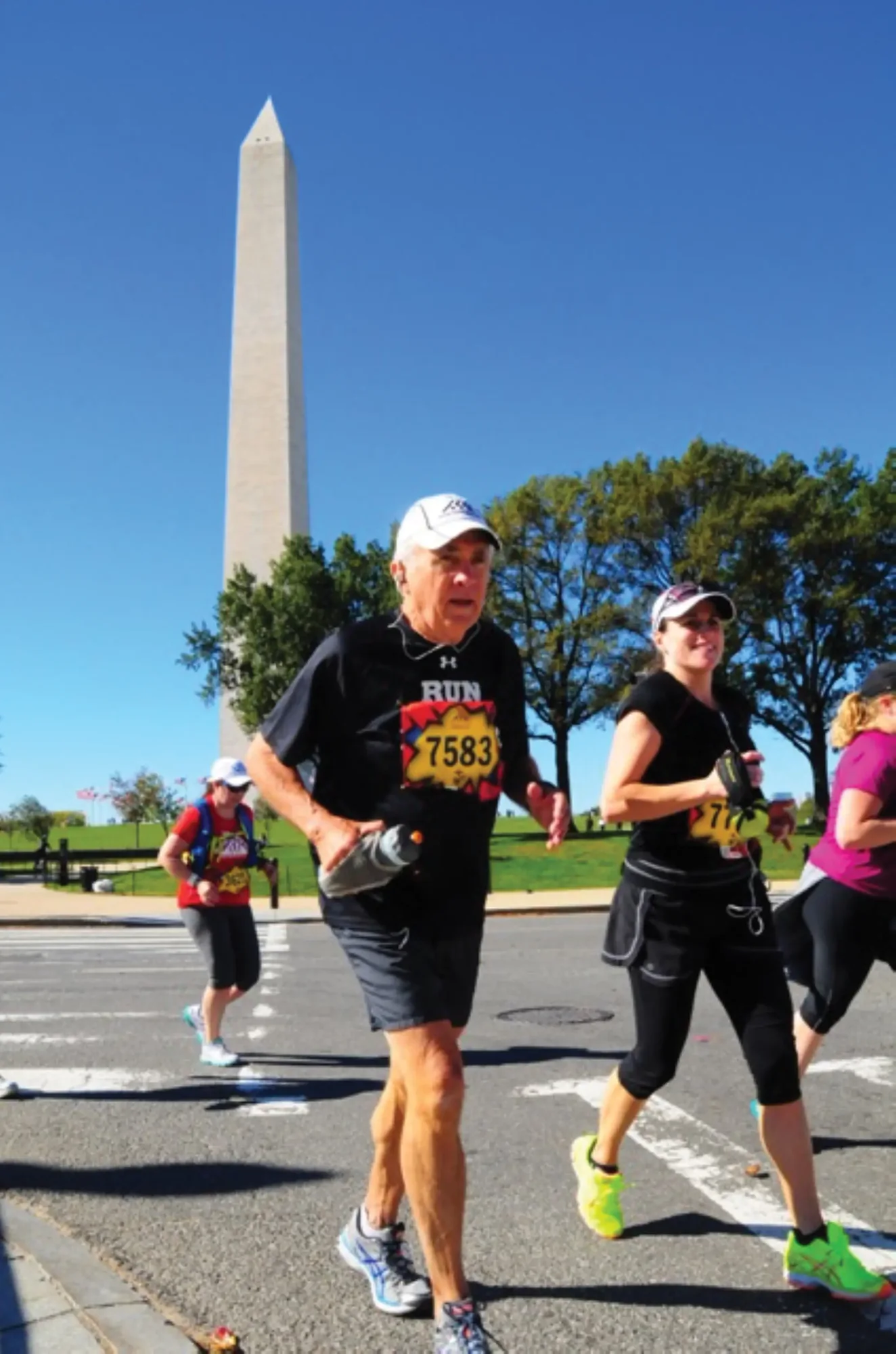 A runner on a marathon course with the Washington Monument behind him.